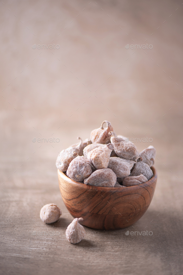 Dry figs in wooden bowl on wood textured background. Copy space. Superfood, vegan, vegetarian food