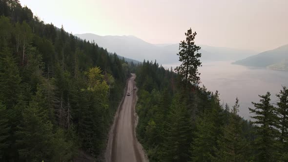 Pick-up truck passing a parked car along a dirt road that leads through British Columbia's vast coni alt