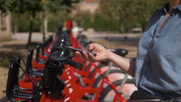 Woman Take Electric Kick Scooter or Bike Bicycle in Sharing Parking Lot Tourist Phone Application alt