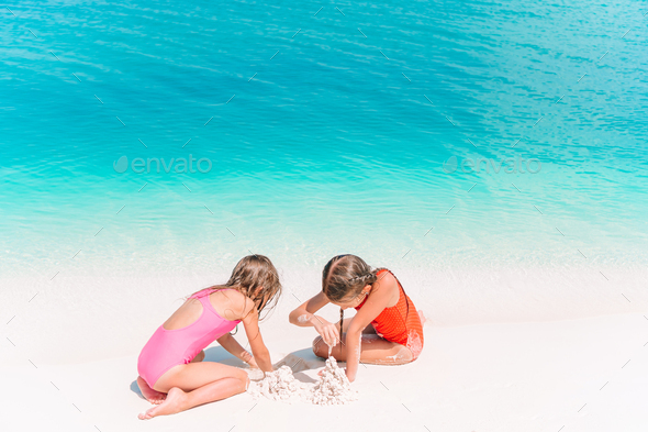 Two little happy girls have a lot of fun at tropical beach playing together  Stock Photo by travnikovstudio