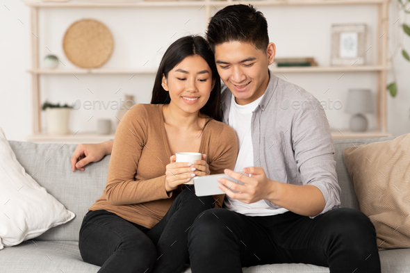 Korean couple resting at home, using phone