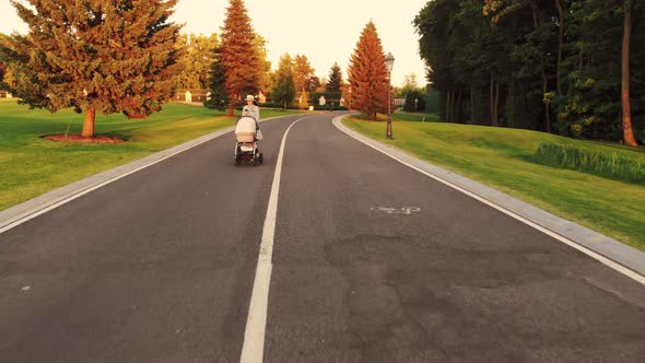 Front View of Young Mother with Baby Carriage and Phone alt