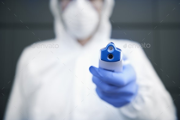 Technician in clean suit holding a non-contact thermometer