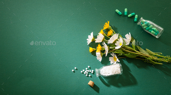Homeopathy, globules and pills on green background Stock Photo by rawf8