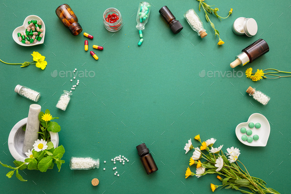 Homeopathy, globules and herbs on green background Stock Photo by rawf8