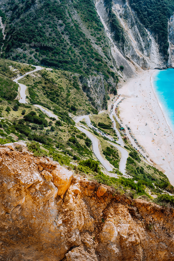 Serpentine zigzag road down to famous Myrtos Beach. Orange rocks ravine on side. Sunny beach from - Stock Photo - Images