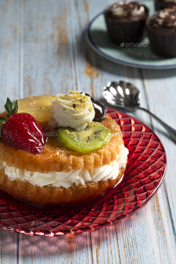 Baba with rum syrup and fresh fruits with whipped cream Stock Photo by