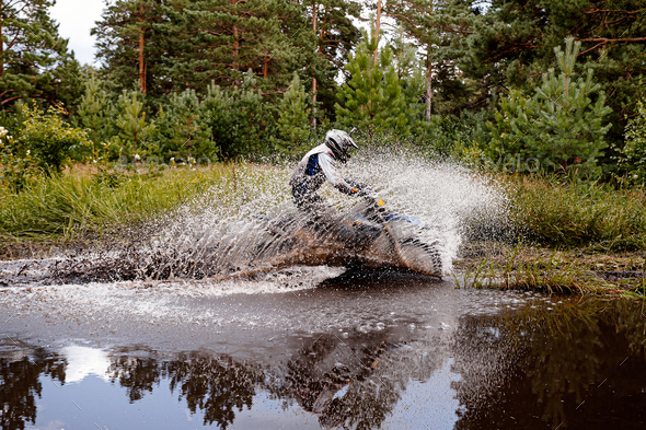 motocross rider riding a puddle in forest trail