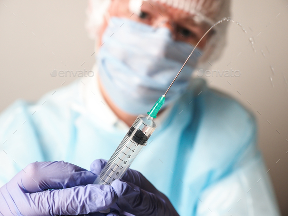 Doctor wearing mask and gloves with a syringe