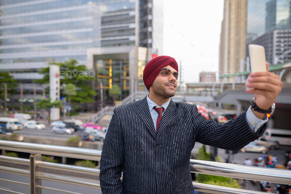Indian businessman with turban outdoors in city using mobile phone