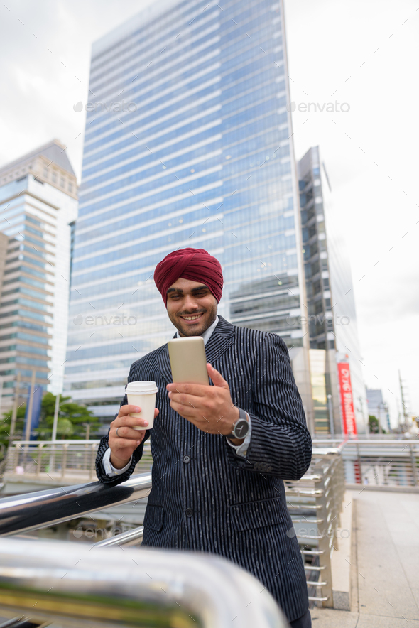 Indian businessman with turban outdoors in city using mobile phone