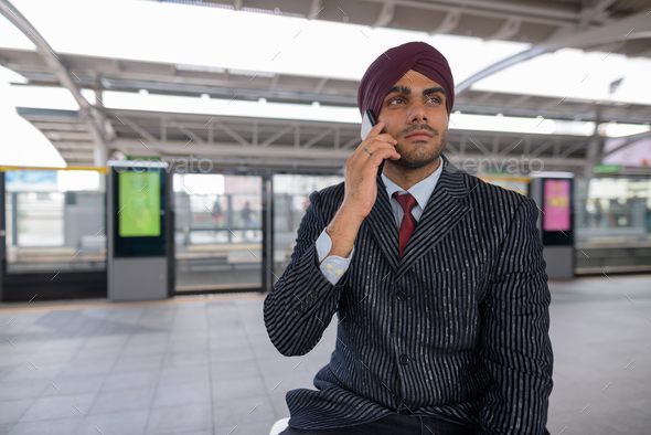 Indian businessman talking on phone at train station