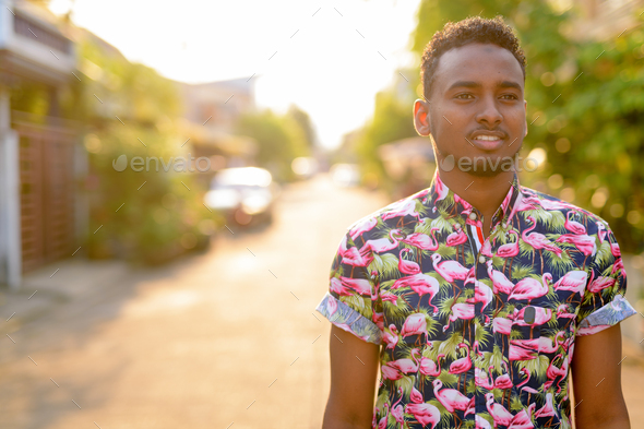 Face of young happy African tourist man thinking outdoors