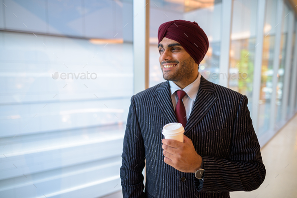 Happy Indian businessman with turban looking through window