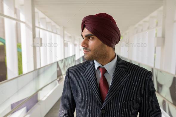 Portrait of Indian businessman with turban thinking outdoors in city