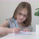 Little School Girl Wearing Glasses Sitting at Table Doing Homework - VideoHive Item for Sale