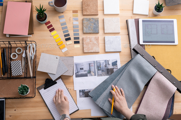Flat lay of hands of contemporary creative interior designer over workplace