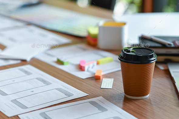 An application designer desk with a mobile screen sketch and take away coffee in the home office.