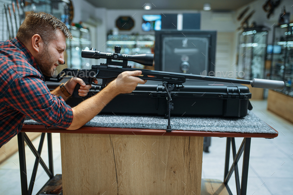 Man aims with sniper rifle in gun shop