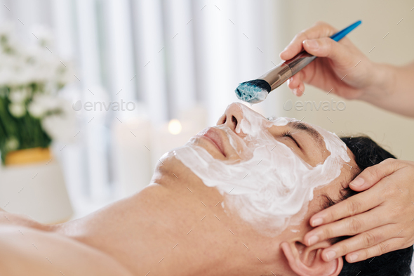Cosmetologist applying rejuvenating mask