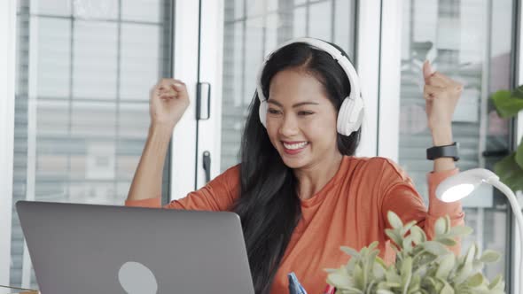 Beautiful Asian businesswoman celebration of a successful job while sitting at the workplace.