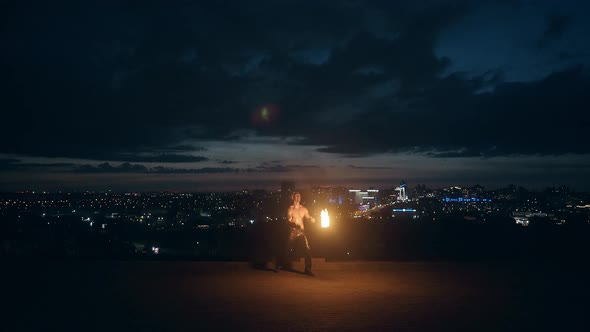 Young Blond Male Does Tricks with Fire, Breaths Fireball in the Middle of the Night with City alt