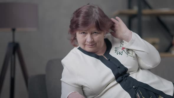 Portrait of Confident Senior Redhead Caucasian Woman Posing Lying on Couch in Living Room Looking at alt