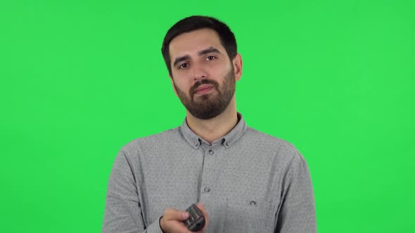 Portrait of Brunette Guy with TV Remote in His Hand, Switching on TV. Green Screen alt