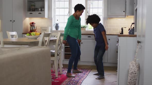 Mixed race female couple and daughter dancing in kitchen alt