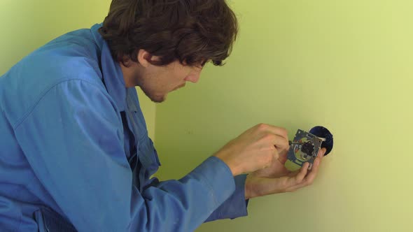 Medium Shot of Young Professional Electrician Doing Socket Repair. alt