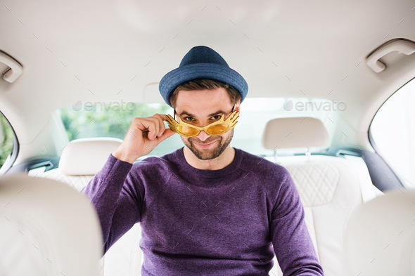 Cheerful man with party accessories sitting in car, having fun - Stock Photo - Images