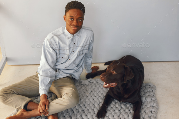 Handsome black man sitting on a blue background with a dog