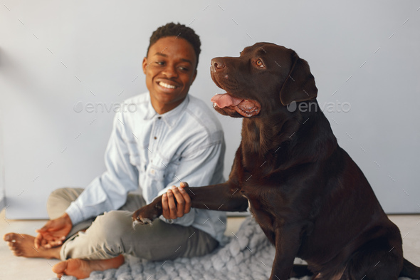 Handsome black man sitting on a blue background with a dog
