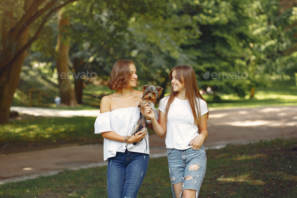 Two cute girls in a park playing with little dog