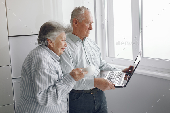 Elegant old couple at home using a laptop