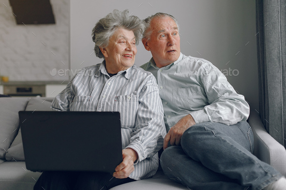 Elegant old couple sitting at home and using a laptop