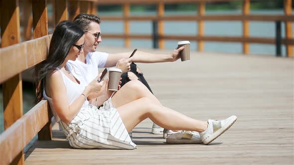 Picture of a Joyful Couple Using Smartphones in the Park alt