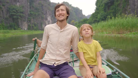 A Young Man and His Son on a Boat Having a River Trip Among Spectacular Limestone Rocks in Ninh Binh alt