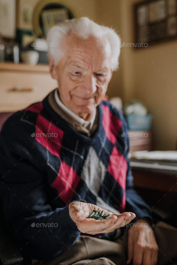 Old man holding handful of green pills in hand - Stock Photo - Images