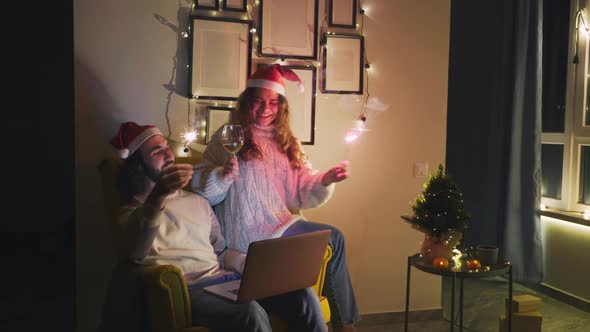 Joyful Couple Holds Flashing Sparklers at Black Laptop