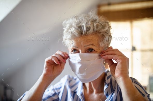 Senior woman with face mask indoors at home, corona virus and quarantine concept