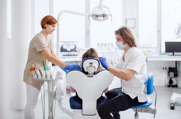 Man dentist and dental assistant at work in surgery, annual check-up