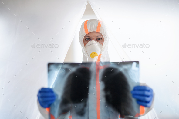 Doctor with protective suit and lungs X-ray in hospital, coronavirus concept