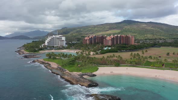 Aerial dolly shot along coastal lagoons with luxury resorts in the background on the island of O'ahu alt