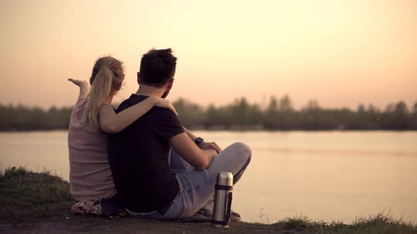 Couple On Sunset.Couple Relaxing On River. Lovers Sitting On Sunset..Happy Couple In Love alt