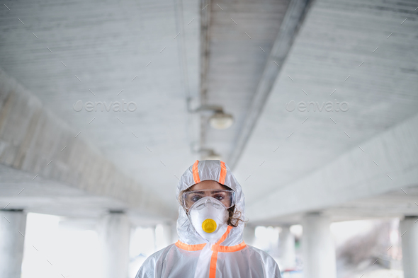 Woman with protective suit and respirator standing outdoors, coronavirus concept.