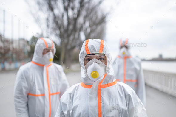 People with protective suits and respirators outdoors, coronavirus concept