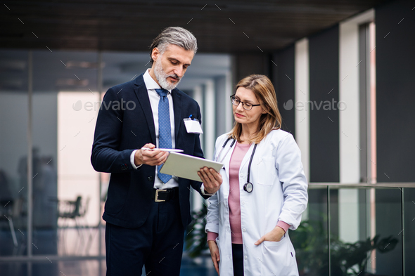 Pharmaceutical sales representative with tablet talking to doctor