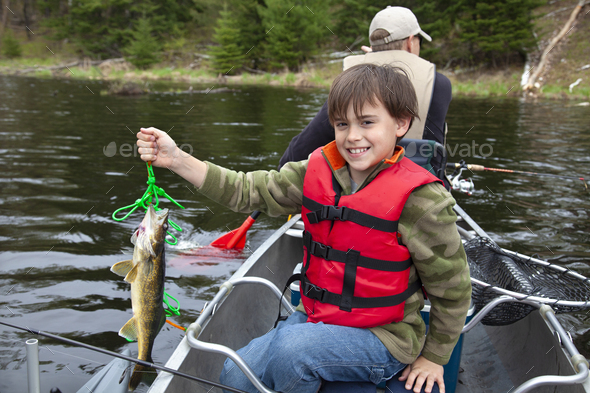 Young boy fisherman in a canoe holds up first walleye of the day Stock ...