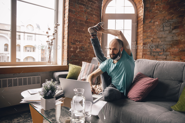 Young man doing yoga at home while being quarantine and freelance working - Stock Photo - Images